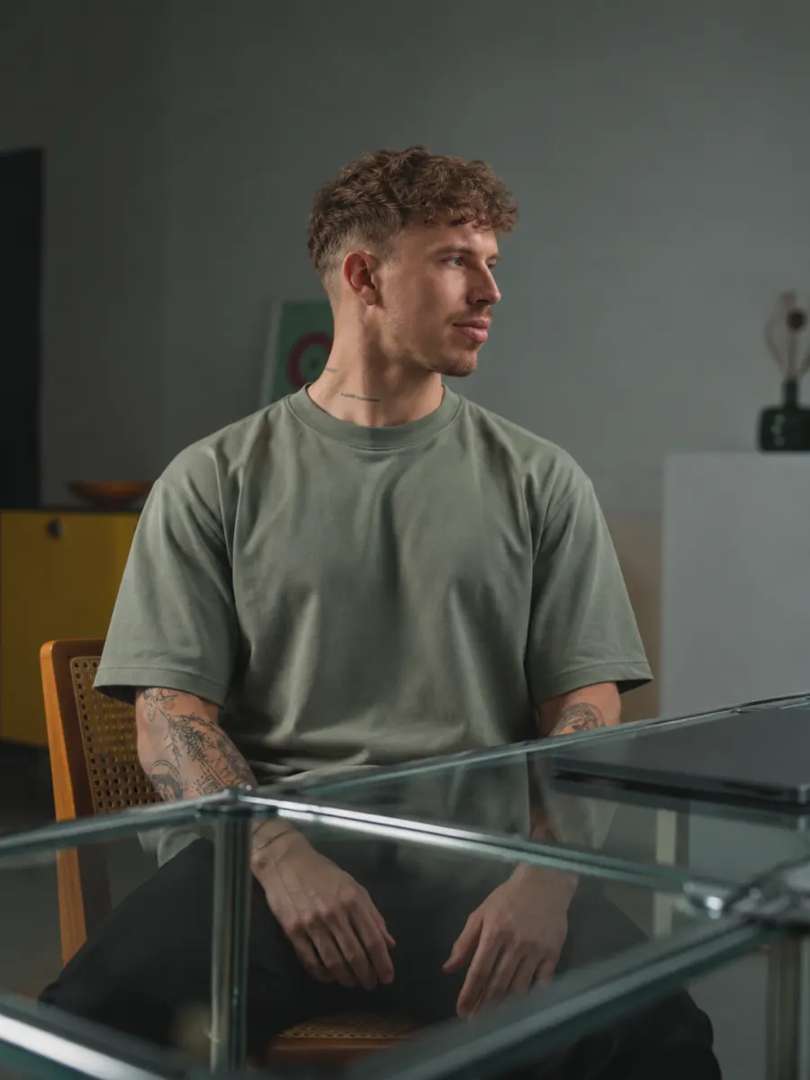 Chris sitzt mittags am Schreibtisch und dreht den Kopf sanft zur Seite.